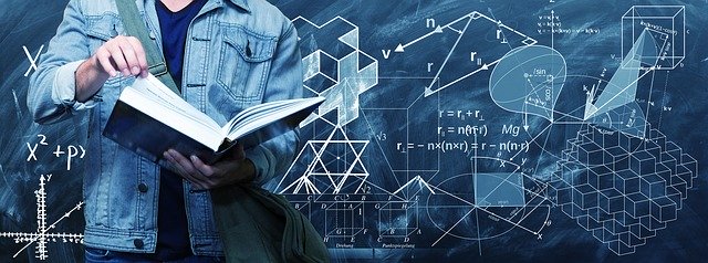 A person in a denim jacket holding an open book stands in front of a blackboard filled with mathematical formulae,...